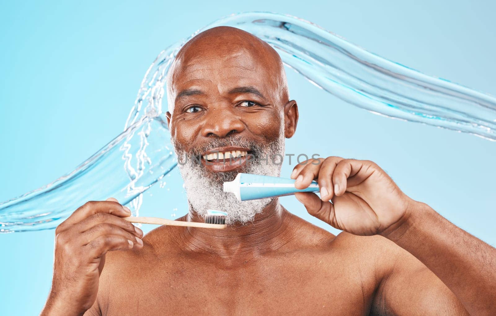 Water splash, oral hygiene and portrait of a man in a studio for mouth health and wellness. Toothpaste, toothbrush and elderly African guy brushing his teeth for fresh dental care by blue background