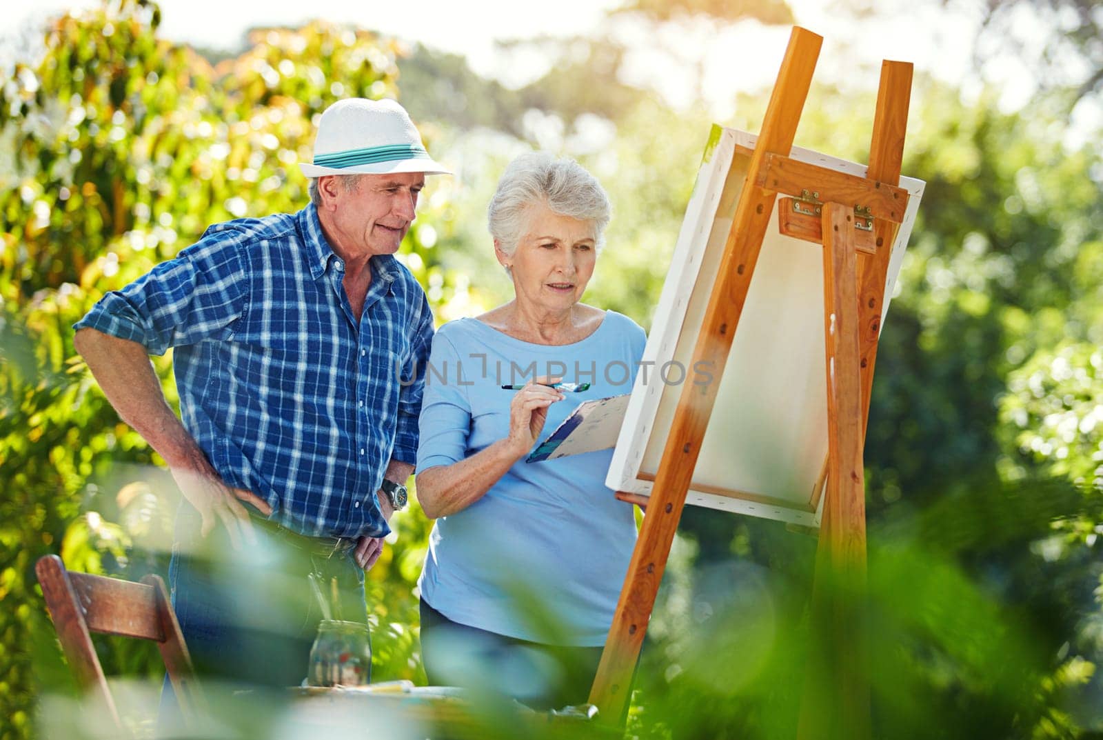 Her painting will be perfect. a senior couple painting in the park. by YuriArcurs