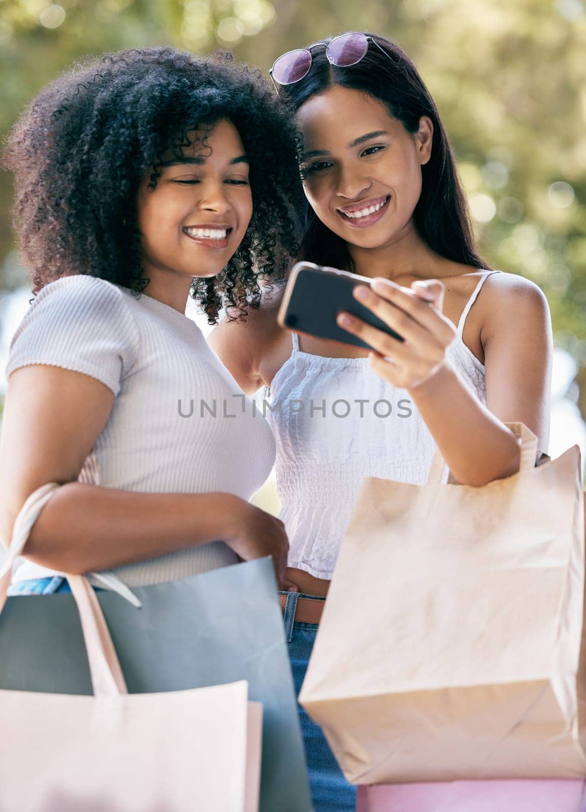 Phone selfie, retail bag and shopping friends post memory picture, gift present or discount sales purchase to social media app. Mobile tech, commerce service or African customer girl on fashion spree by YuriArcurs