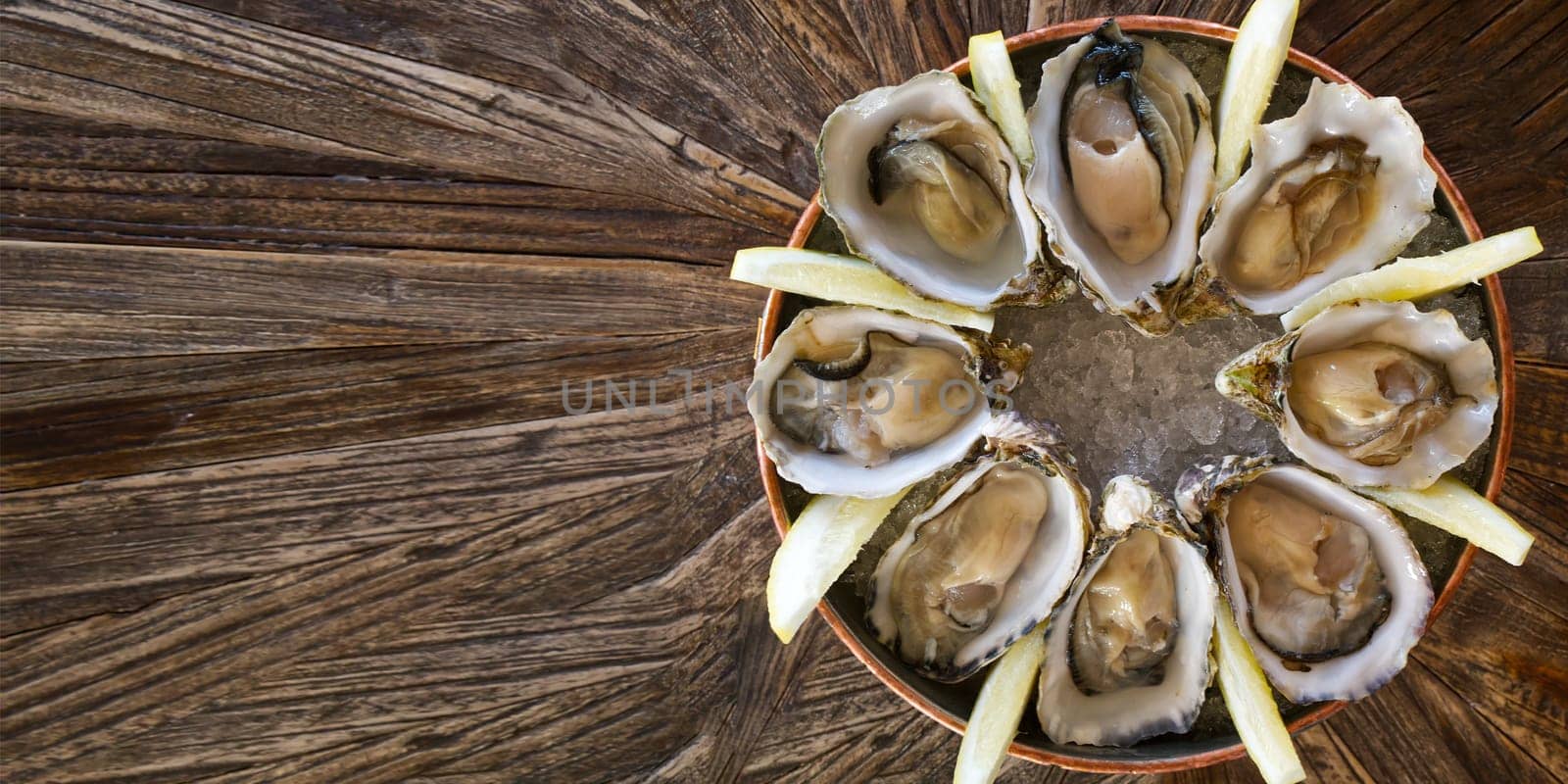 Fresh oysters served on a plate with lemon on old wooden table. Teasty Oysters served in fish restaurant.