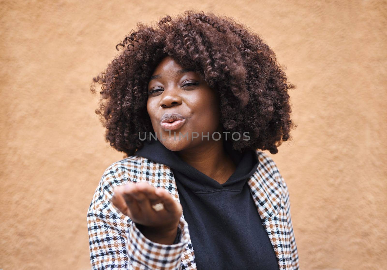 Smile, flirt and black woman blowing a kiss for love and romance with urban fashion. Girl with hands, lips and kissing air, cute and fun celebration of romantic freedom and flirting with happy youth
