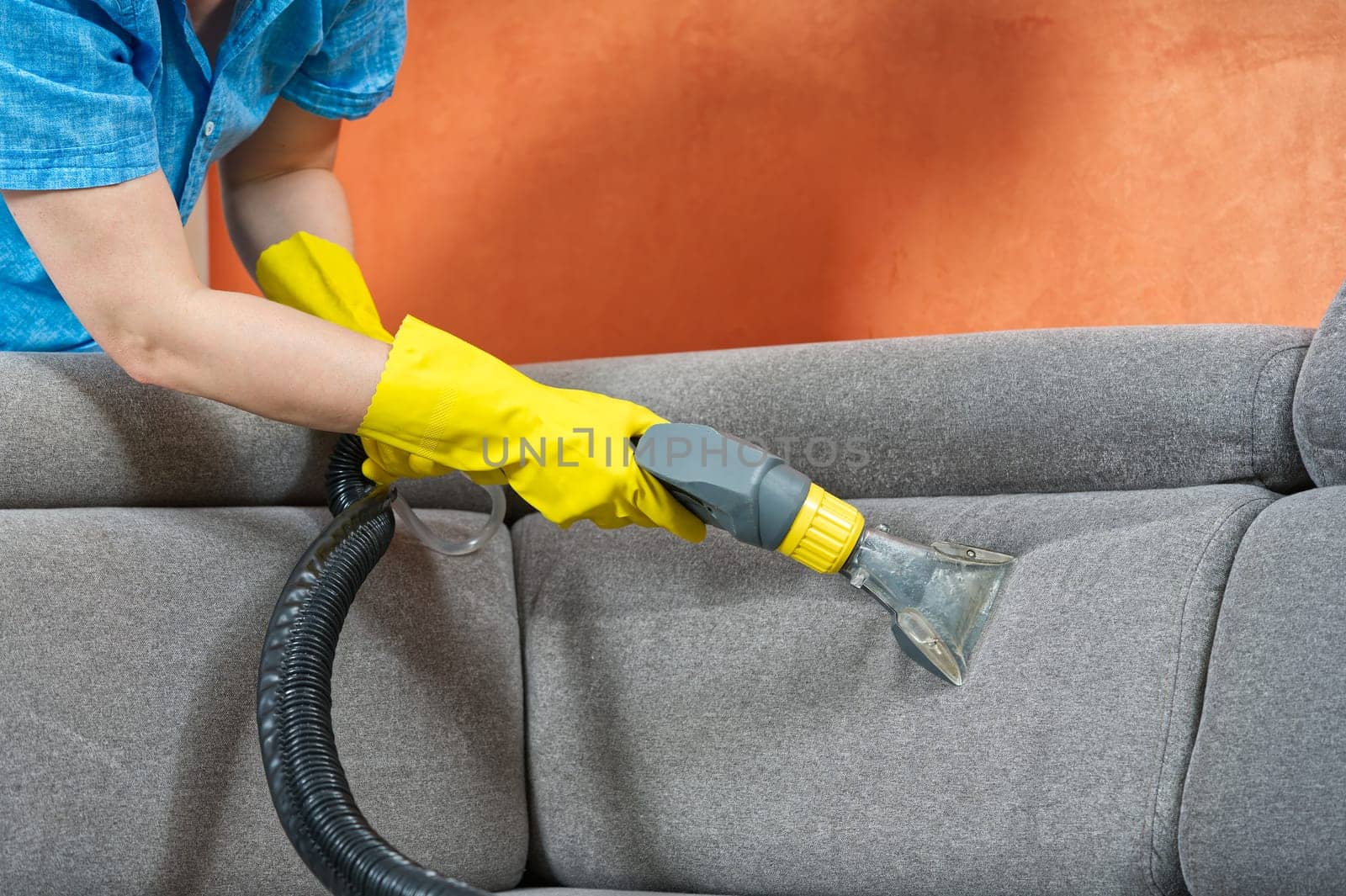 Cleaning concept. Woman washes soft furniture in living room. Employee removing dirt from furniture by PhotoTime