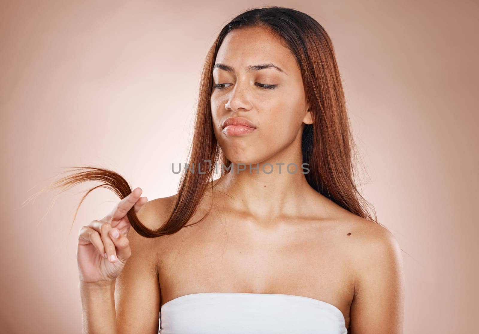 Thinking, hair care and woman with split ends texture checking damage with unhappy face. Frustrated, concerned and problem of beauty cosmetics girl in beige studio background with dry hair.