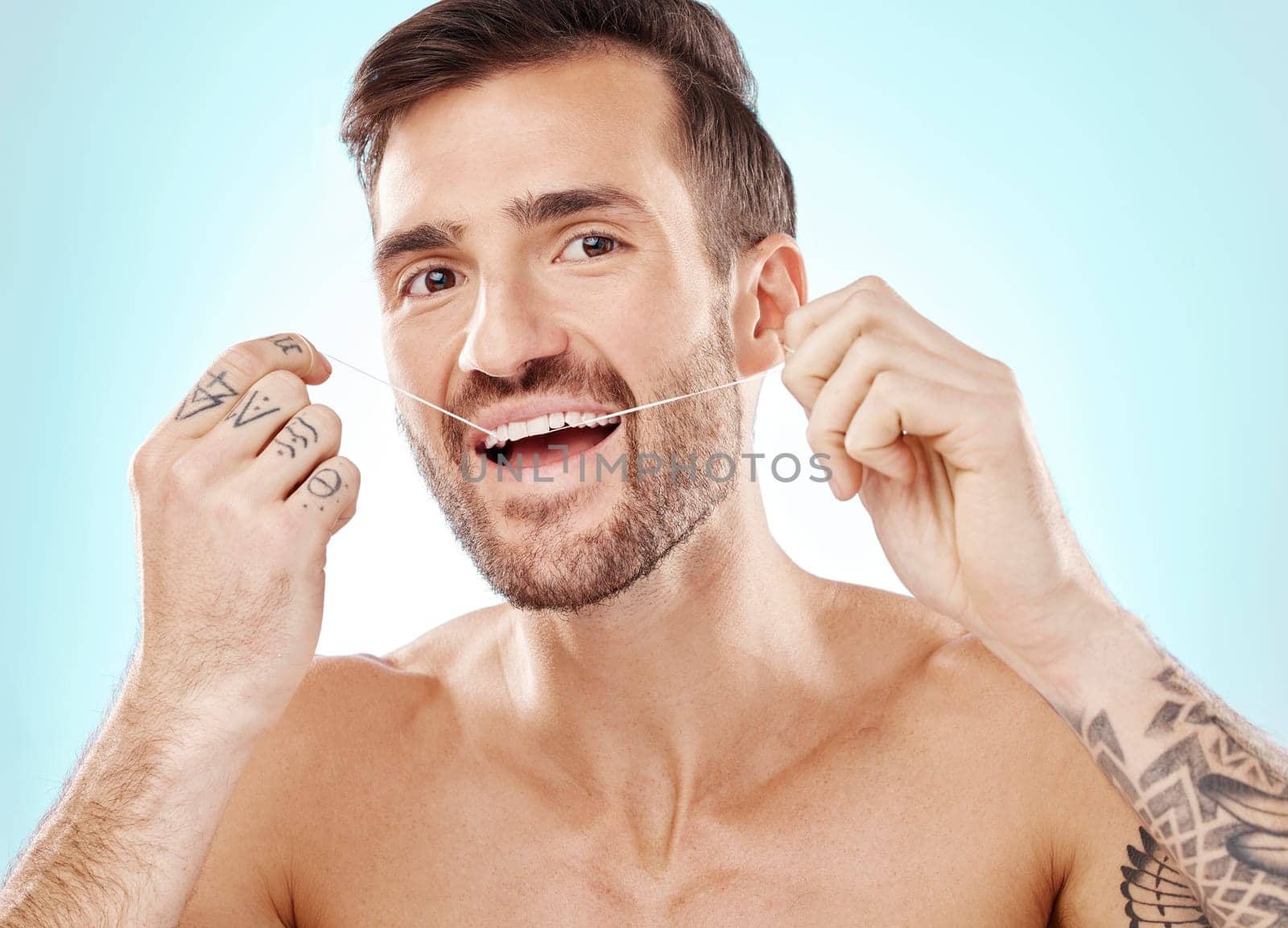 Portrait, face and man with dental floss in studio isolated on a blue background. Oral wellness, hygiene and happy male model flossing teeth for healthy mouth, cleaning or fresh breath and gum care