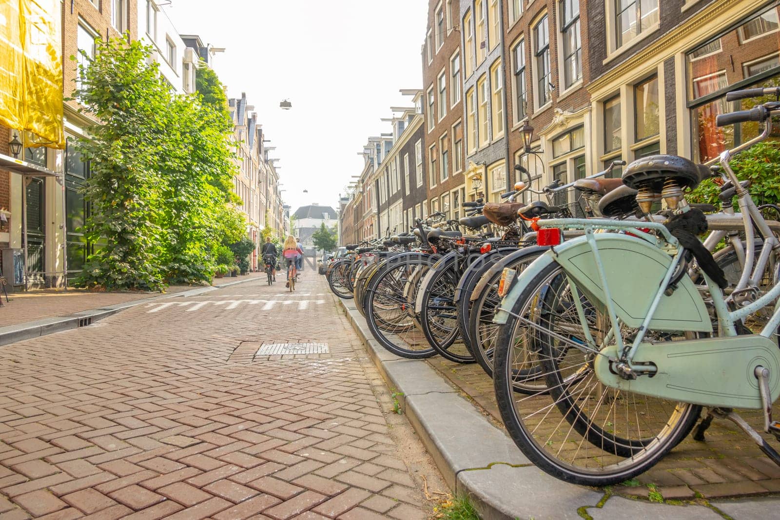 Parked Bikes and a Few Cyclists on an Amsterdam Street by Ruckzack