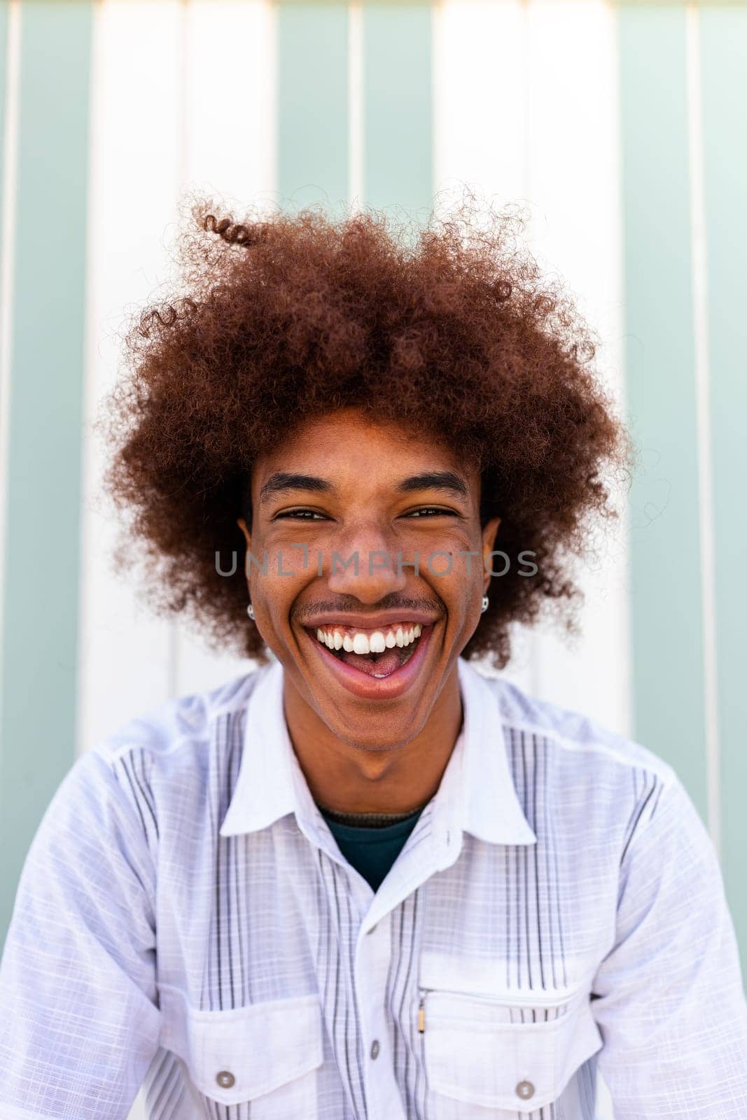 Headshot of happy African American Black young man smiling looking at camera. Summertime. Vertical portrait.