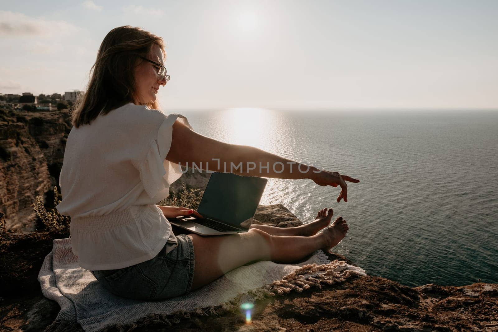 Woman sea laptop. Business woman in yellow hat working on laptop by sea. Close up on hands of pretty lady typing on computer outdoors summer day. Freelance, digital nomad, travel and holidays concept.