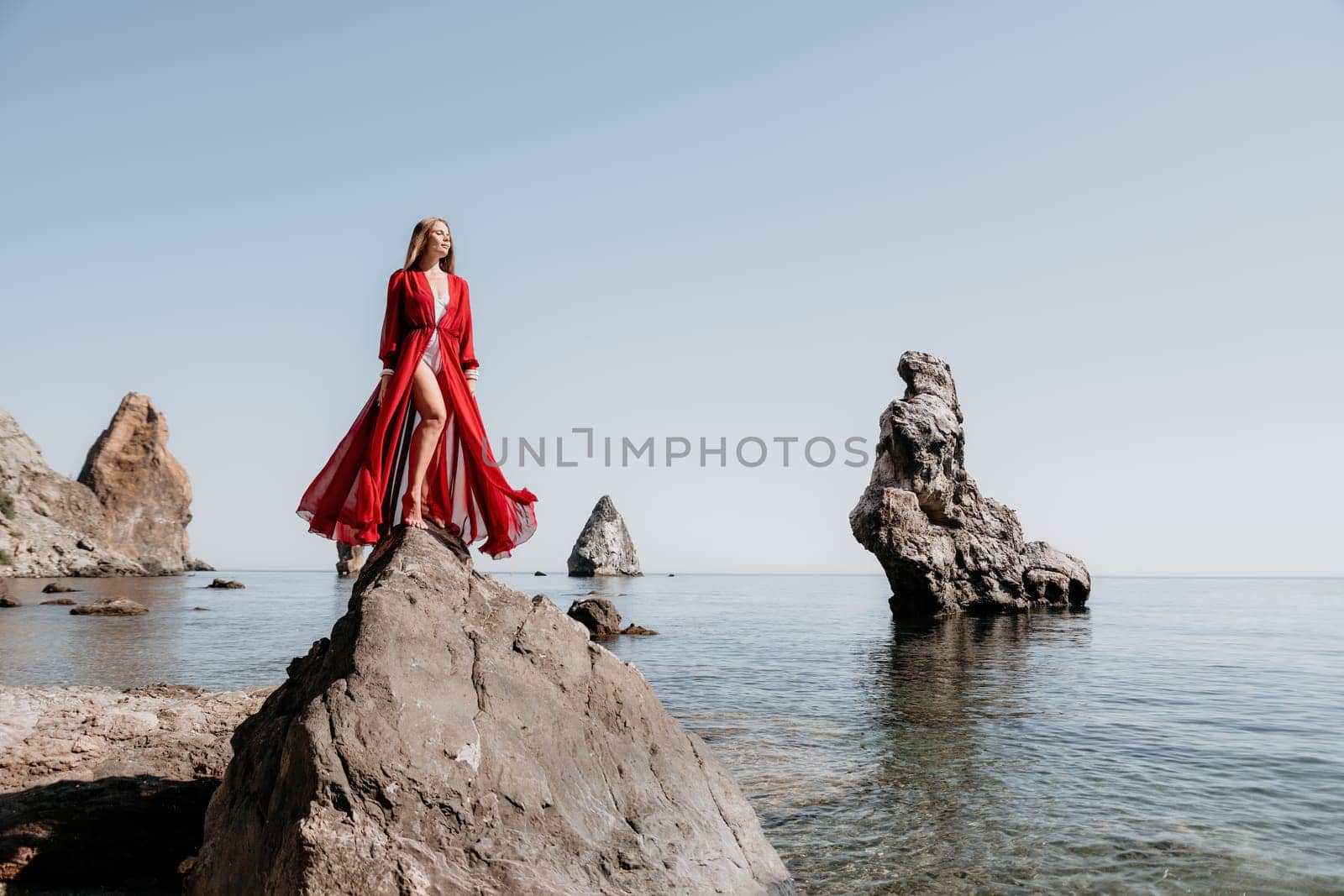 Woman travel sea. Happy tourist taking picture outdoors for memories. Woman traveler looks at the edge of the cliff on the sea bay of mountains, sharing travel adventure journey.