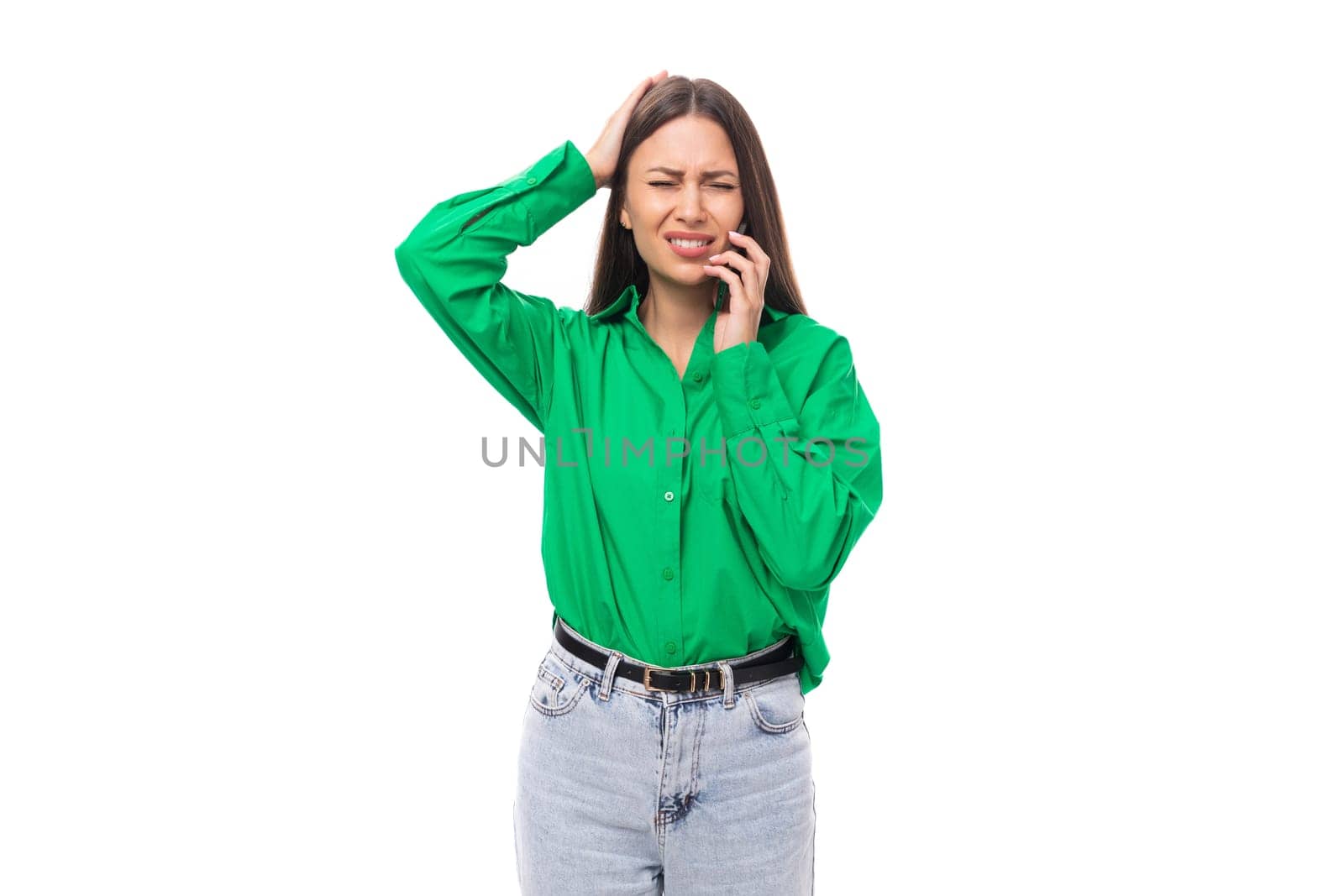 young puzzled european brunette woman with brown eyes in a green blouse on a white background with copy space.