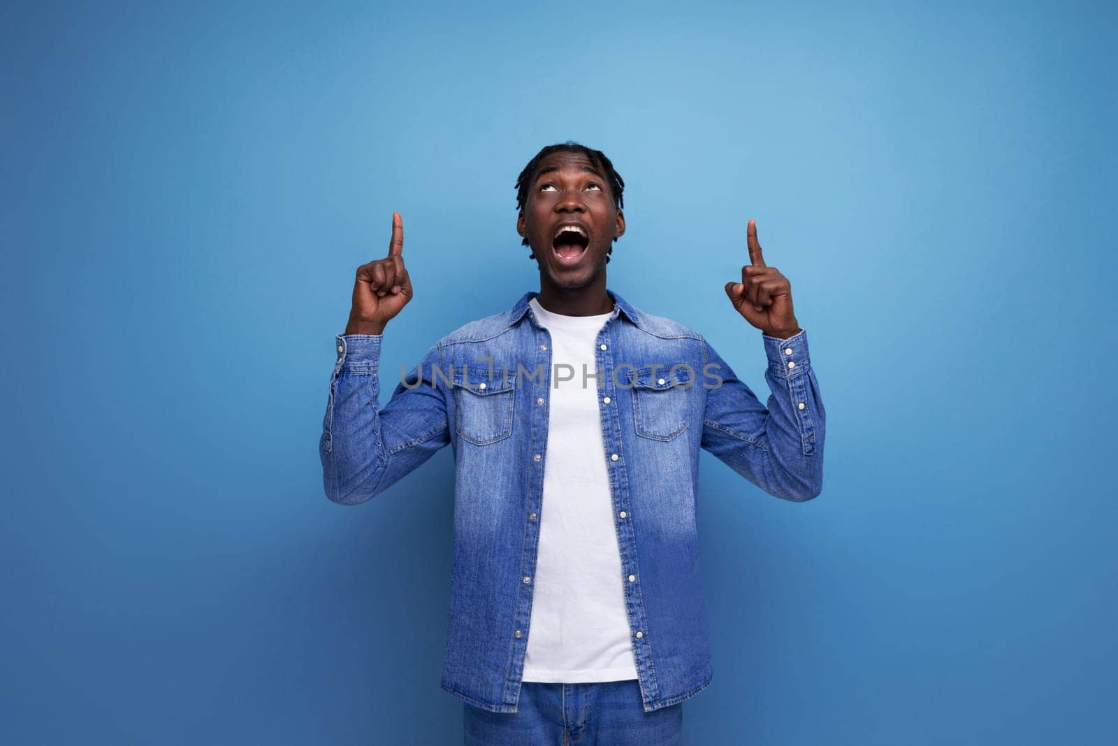 charismatic dude african man with curly hair in a denim jacket on a blue background.