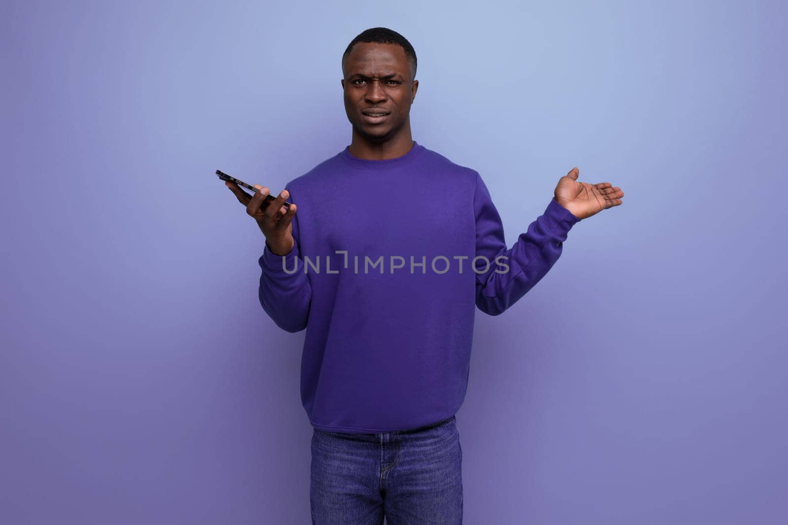 30s American man dressed in a blue sweater looks indignantly at the camera holding a smartphone by TRMK