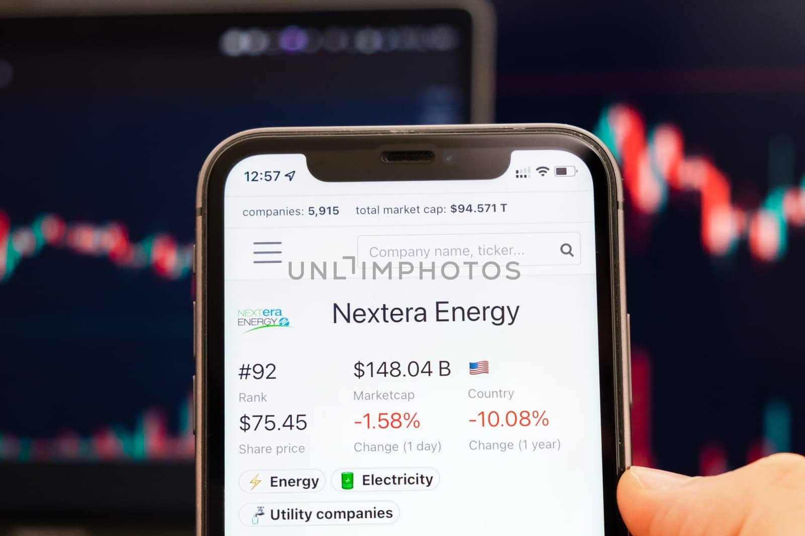 Nextera Energy stock price on the screen of cell phone in mans hand with changing stock market exchange with trading candlestick graph analysis, February 2022, San Francisco, USA