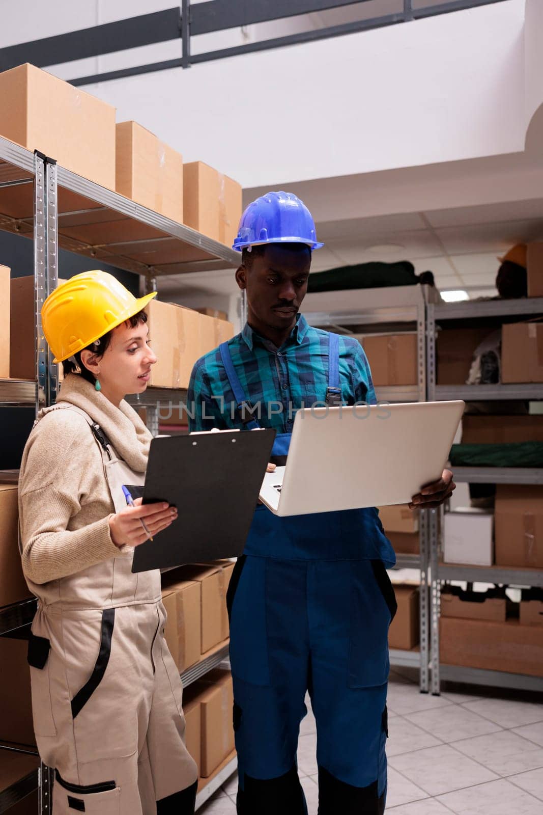 Logistic department warehouse workers monitoring freight distribution on laptop by DCStudio
