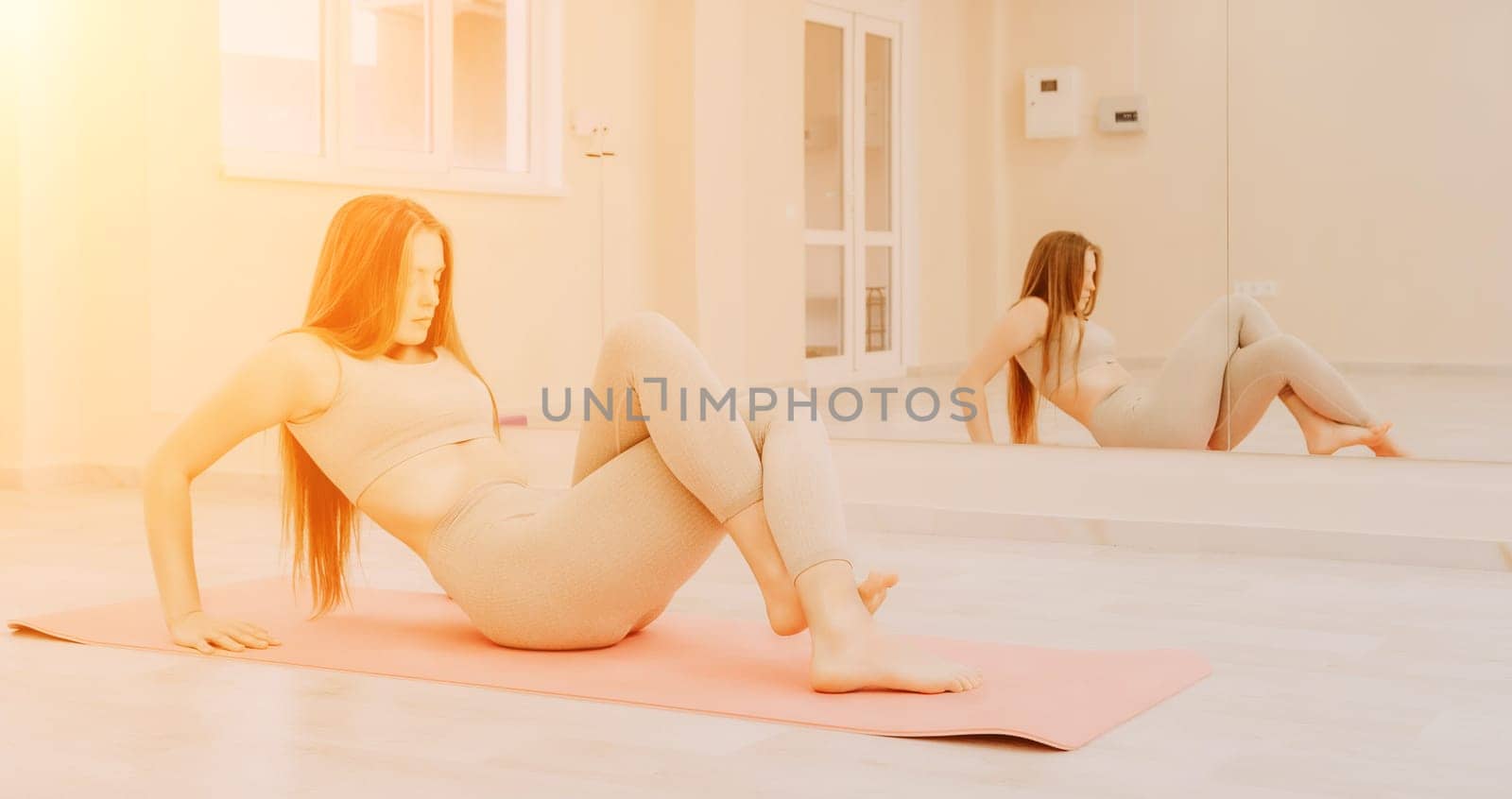 Group of young womans fitness instructor in Sportswear Leggings and Tops, stretching in the gym before pilates, on a yoga mat near the large window on a sunny day, female fitness yoga routine concept.