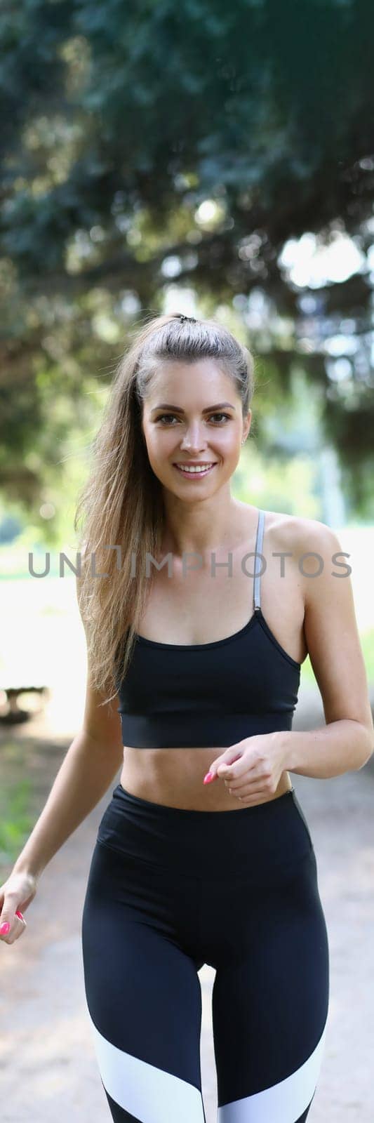 Portrait of happy positive cheerful girl jogging in park. Runner running jogging in park