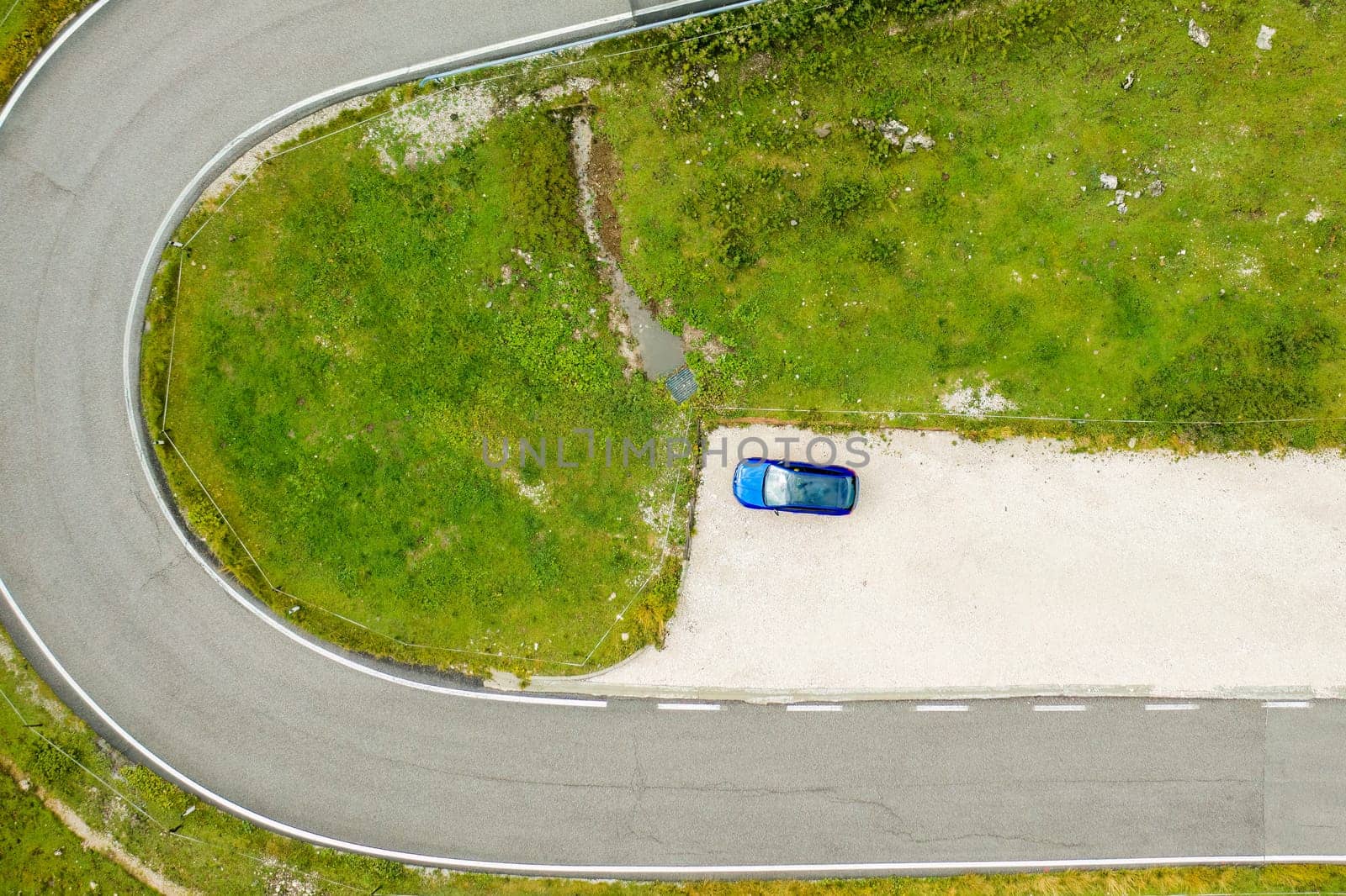 Top view on the blue car stands at the exit by the road near the Giau pass.
