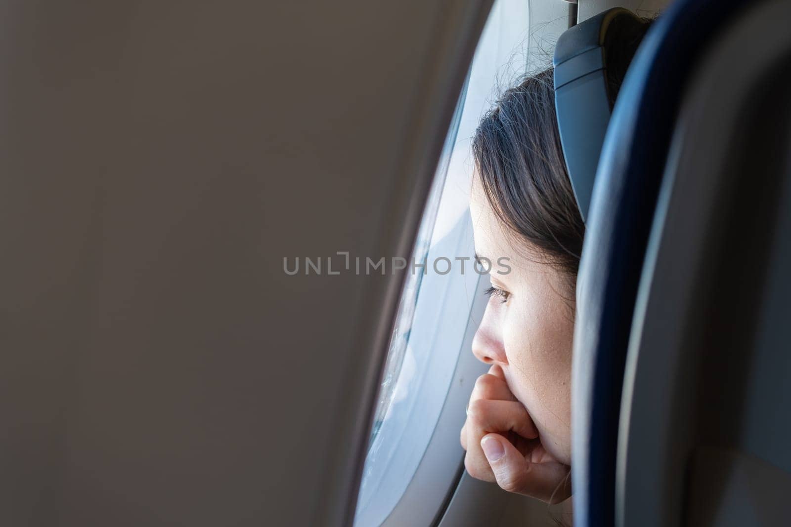 Young woman in headphones looks out the window of the plane, January 2023, Rome, Italy