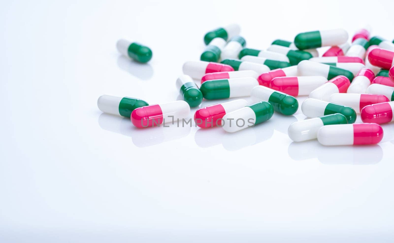 Capsules pill spread on white background. Prescription drugs. Capsule pill production. Green, pink, and white color capsule pills. Pharmaceutical industry. Medication and pharmacology. Health care.