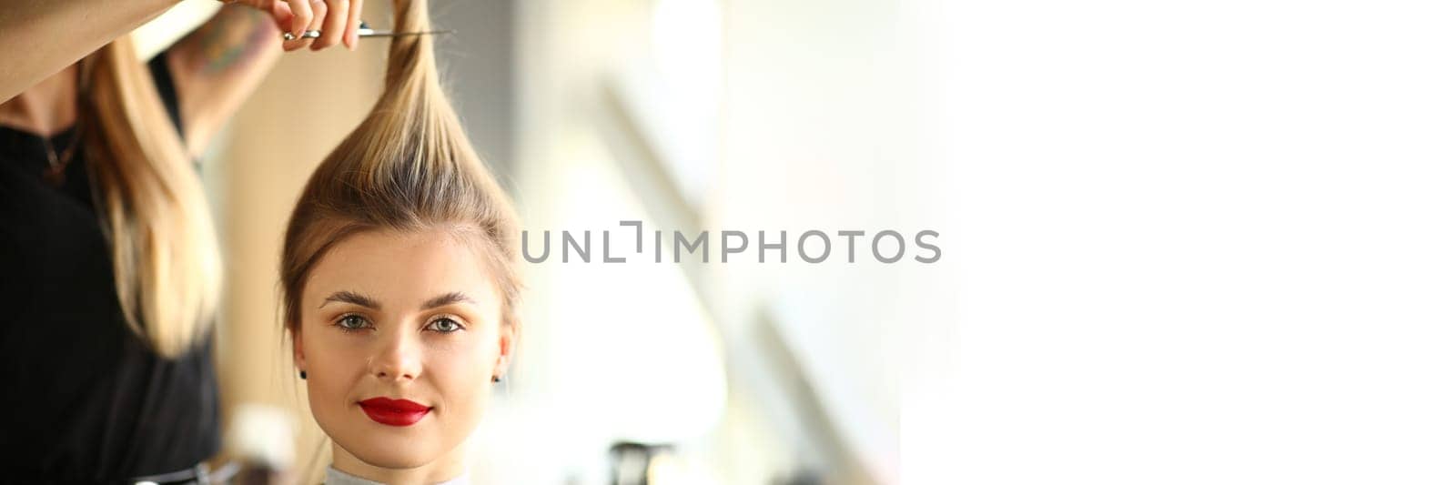 Portrait of blonde woman in hairdressing salon with long ponytail. Master hairdresser cuts hair concept