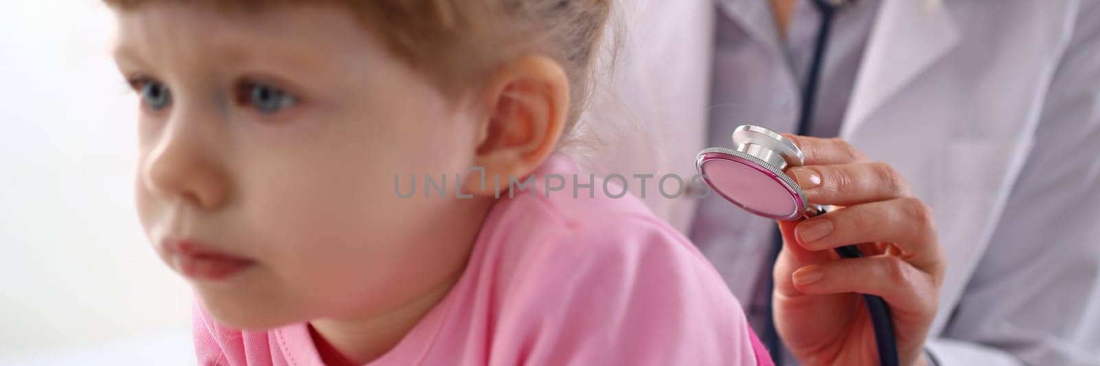 Pediatrician listens to lungs of little girl with stethoscope. Pediatrics medical services and child insurance concept