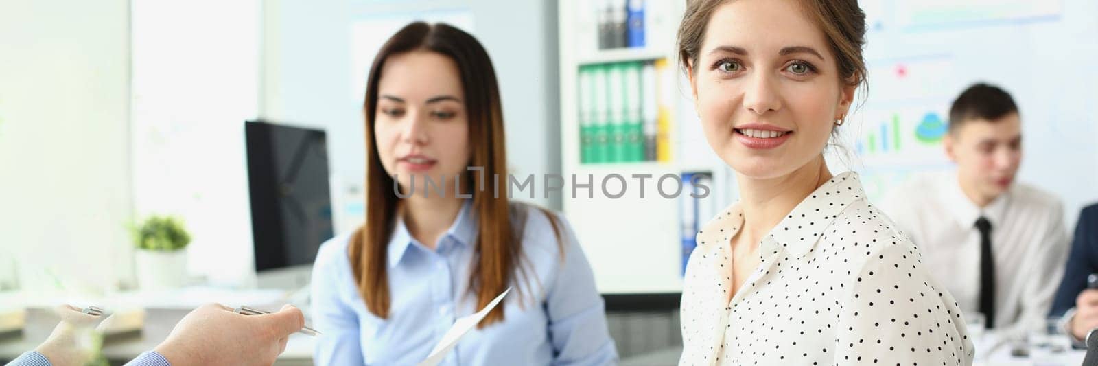 Young beautiful business woman writes in a notebook during seminar. Portrait of female employee listening to executive at corporate meeting and taking notes concept