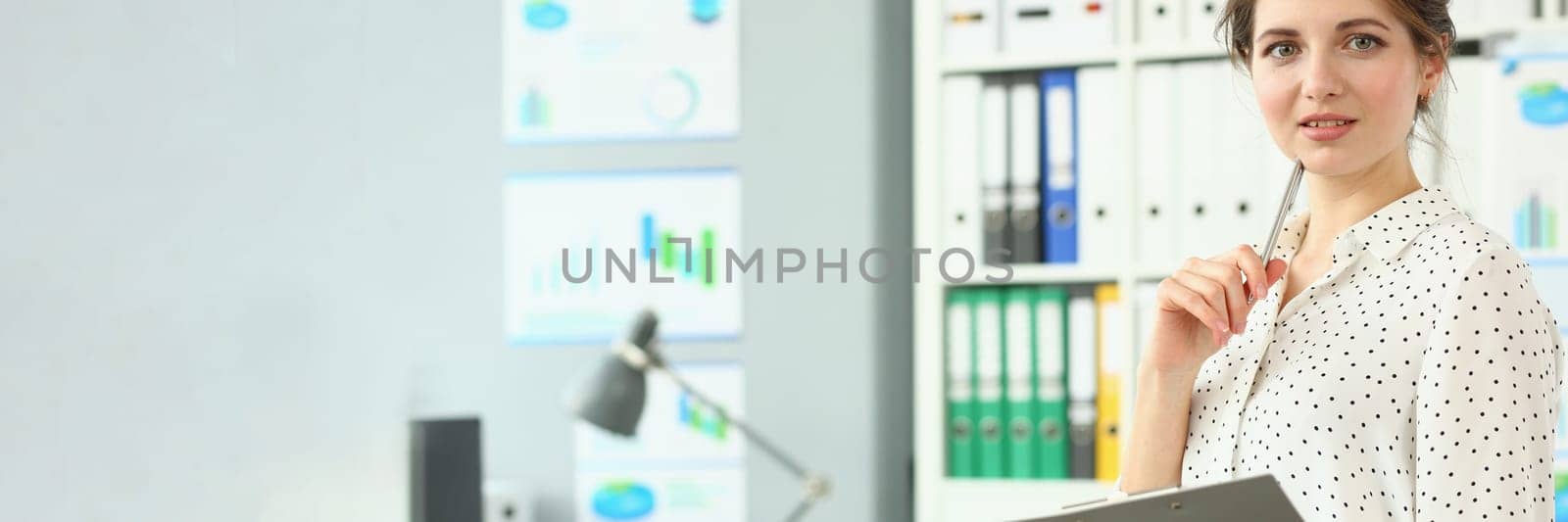 Portrait of smart pensive business woman holding pen and documents in office. Business consultant manager or boss