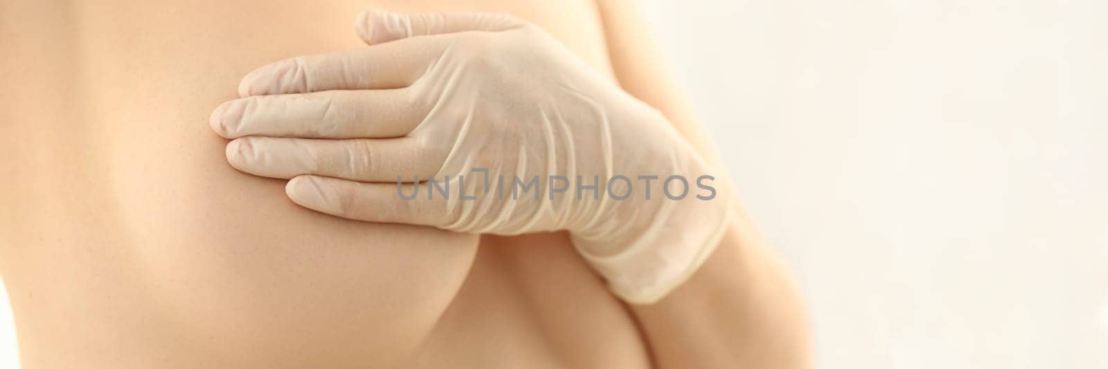 Woman hand in rubber gloves and naked female breast by kuprevich