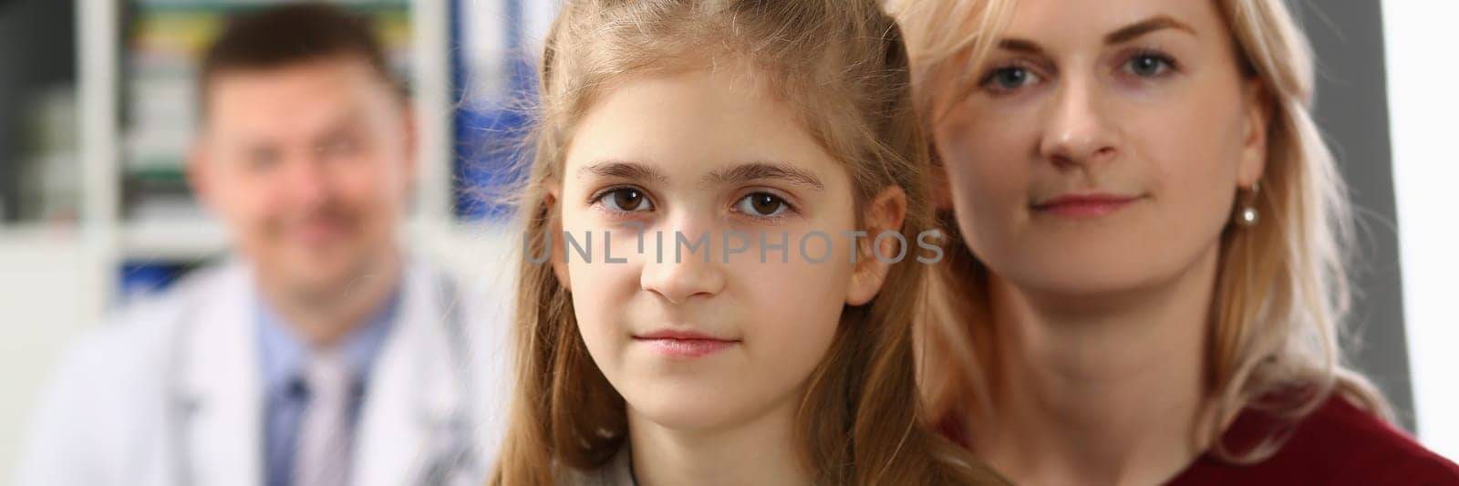 Portrait of mother and daughter on background of pediatrician medical doctor. Medical examination and family insurance concept