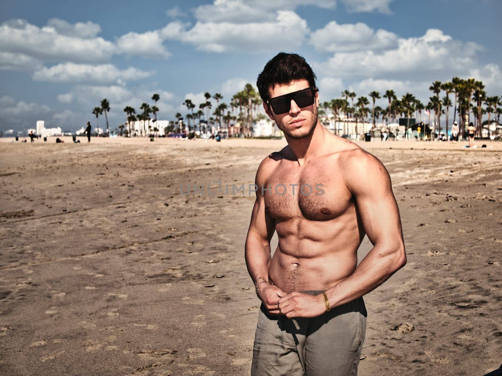 Handsome young man standing on a beach, shirtless wearing boxer shorts, showing muscular fit body in Venice Beach, California, USA