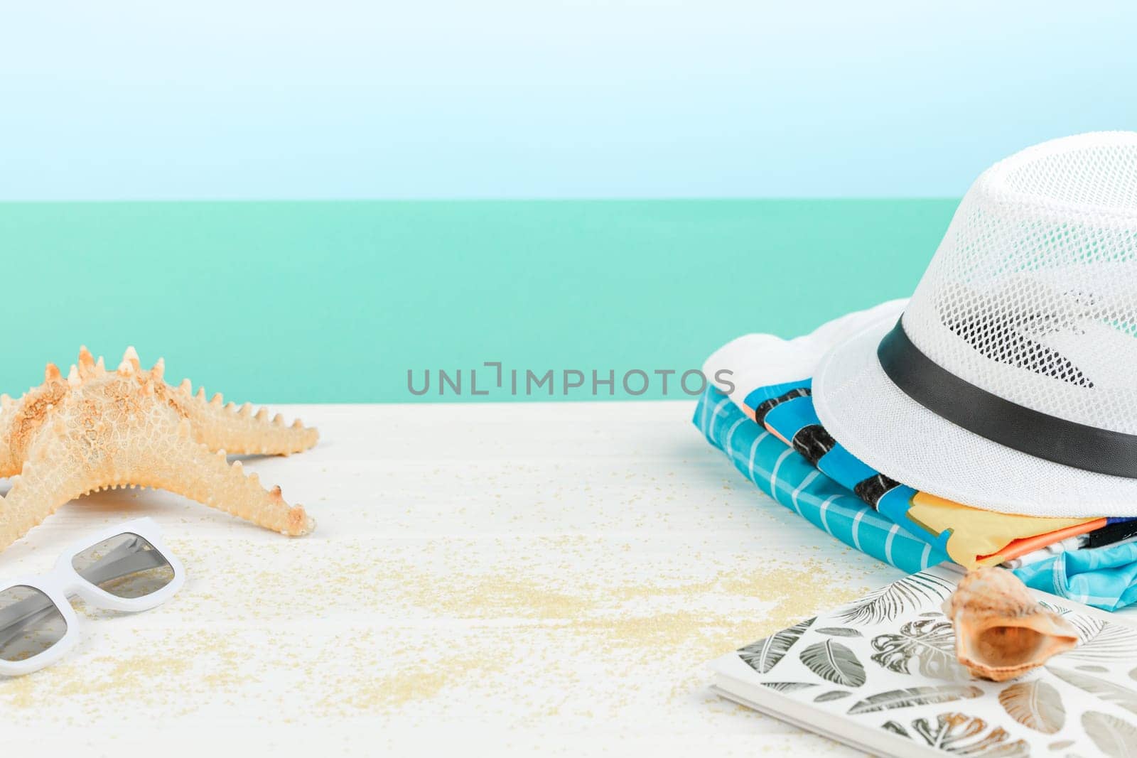 Beach hat with sunglasses and shorts on white wooden background. Summer vacation concept. Starfish and seashells.