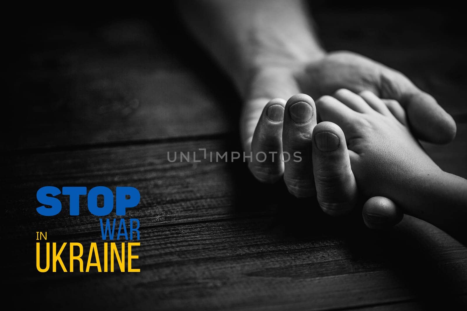 male hands hold childrens on dark wooden background with words stop war in ukraine black and white color. concept needs help and support, truth will win