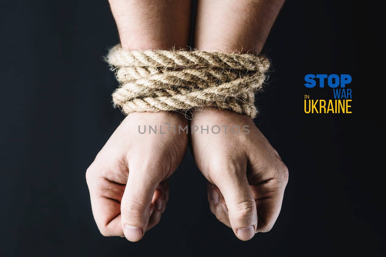 man hands tied with rope on a dark background, violence and kidnapping. with words stop war in ukraine. concept needs help and support, truth will win