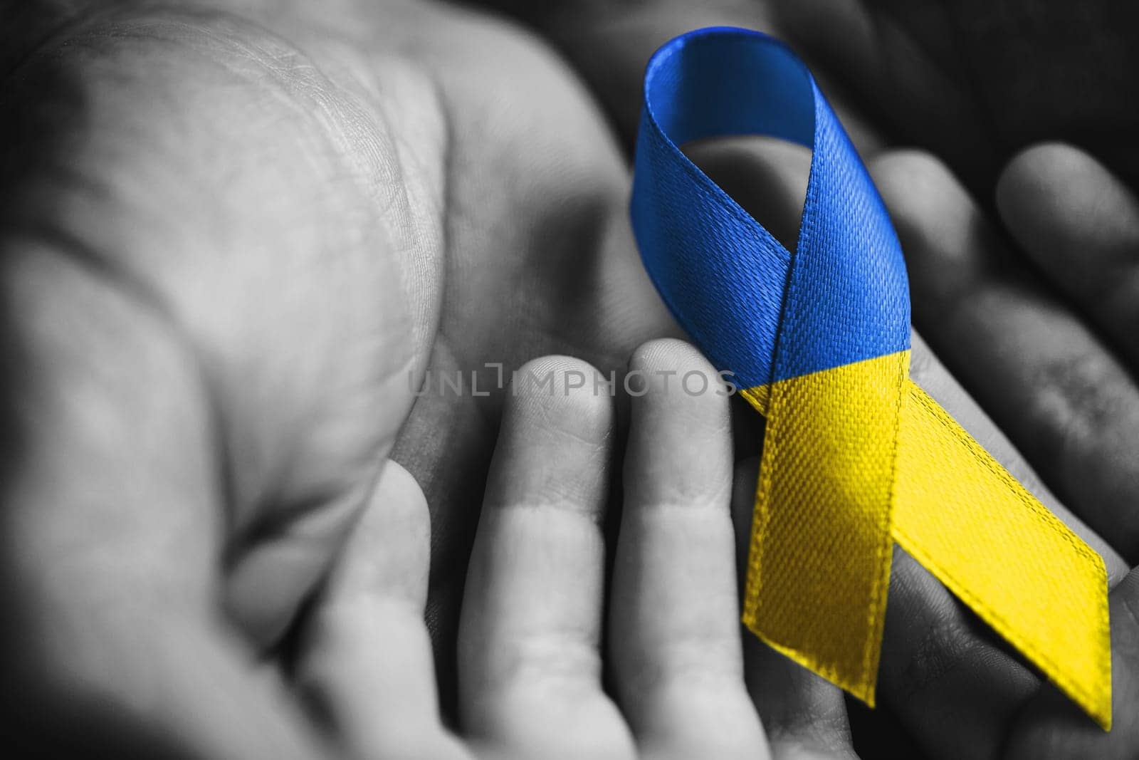 children hands in male hands with ukraine ribbon by alexxndr