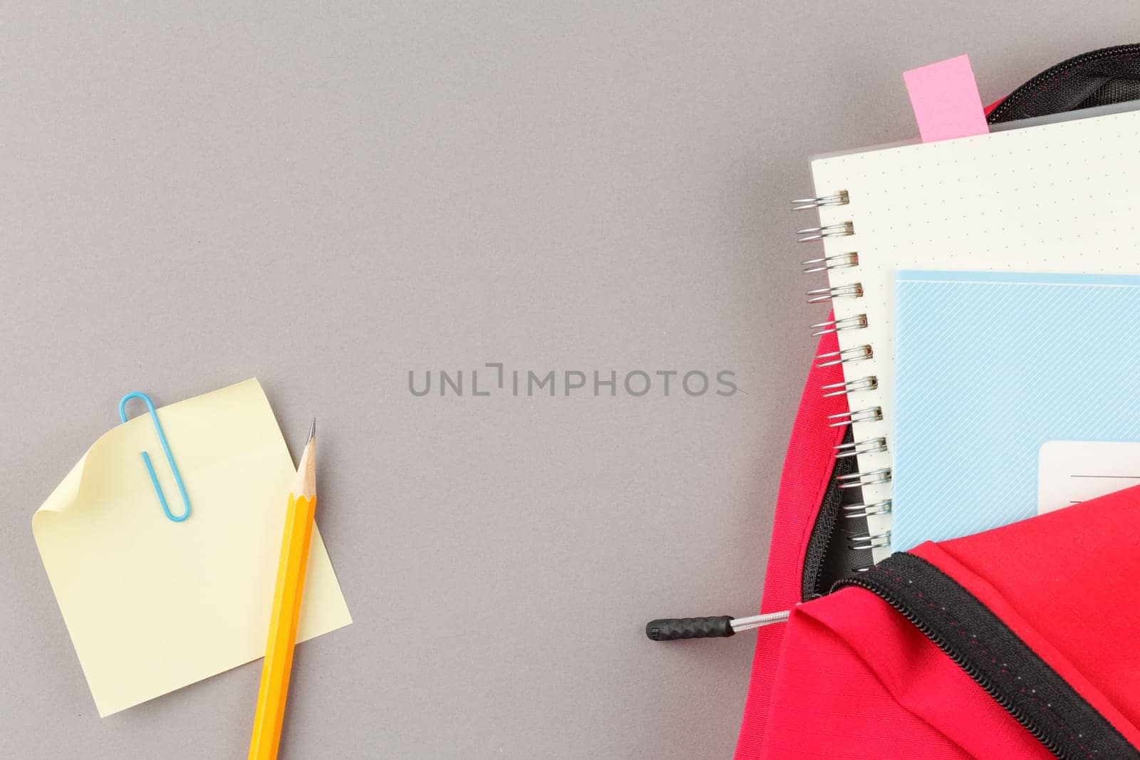 Back to school concept. School backpack with educational supplies on a grey background. Top view. Flat lay student desk.