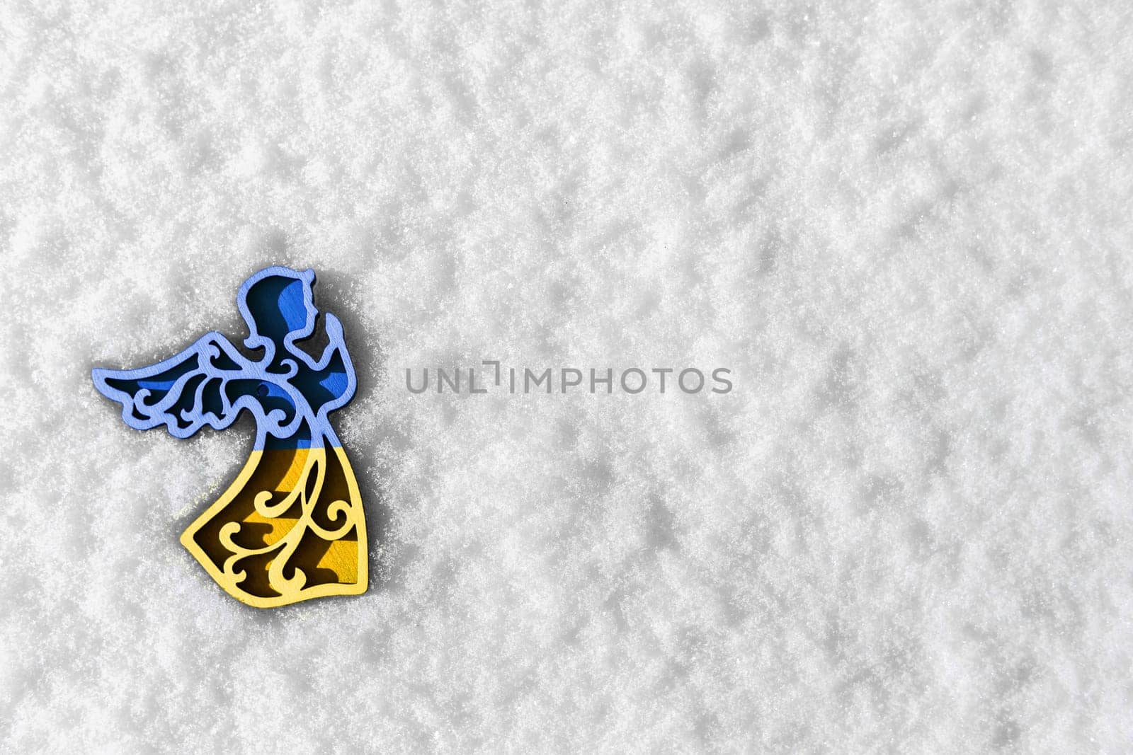yellow blue wooden angel on snow, as symbol of support europe in winter. concept needs help and support, truth will win