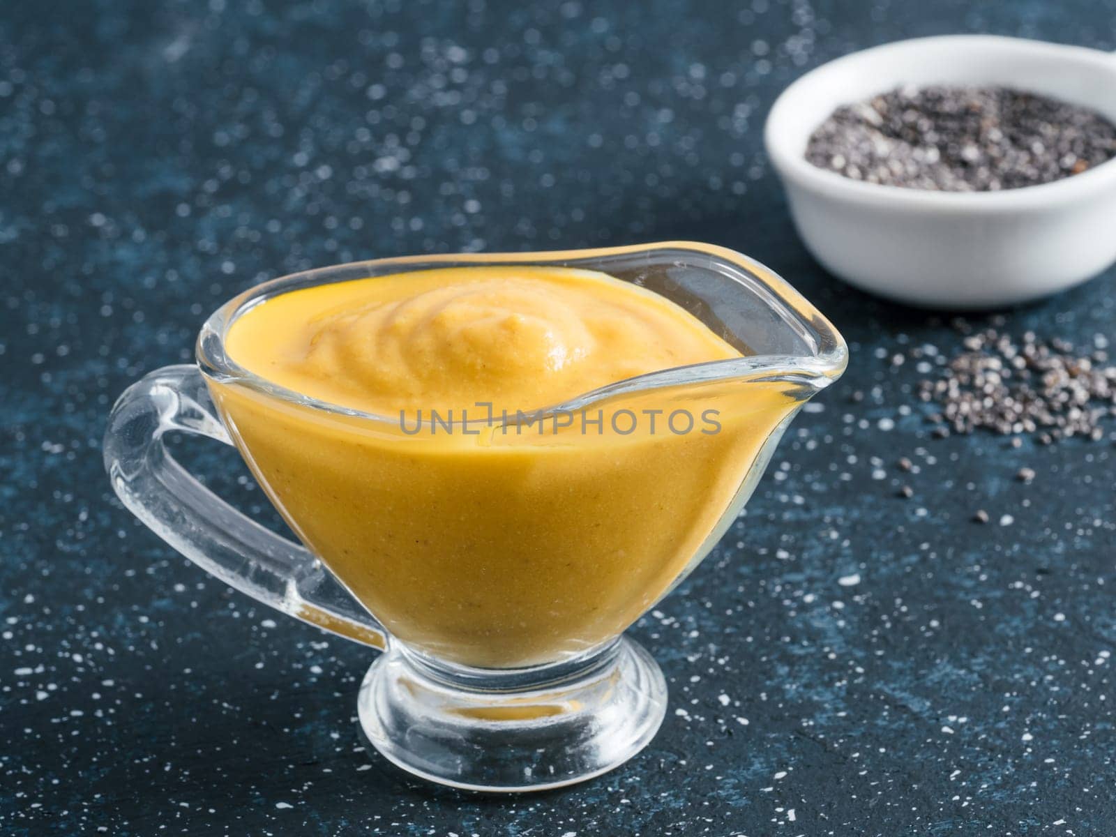Creamy Cheddar sauce with chia seeds on dark background.Ideas and recipe for healthy diet or vegan food.Homemade Chia Cheeze Sauce for snacks,tacos,nachos,dipping,mac-n-cheese,base for pizza.Copyspace