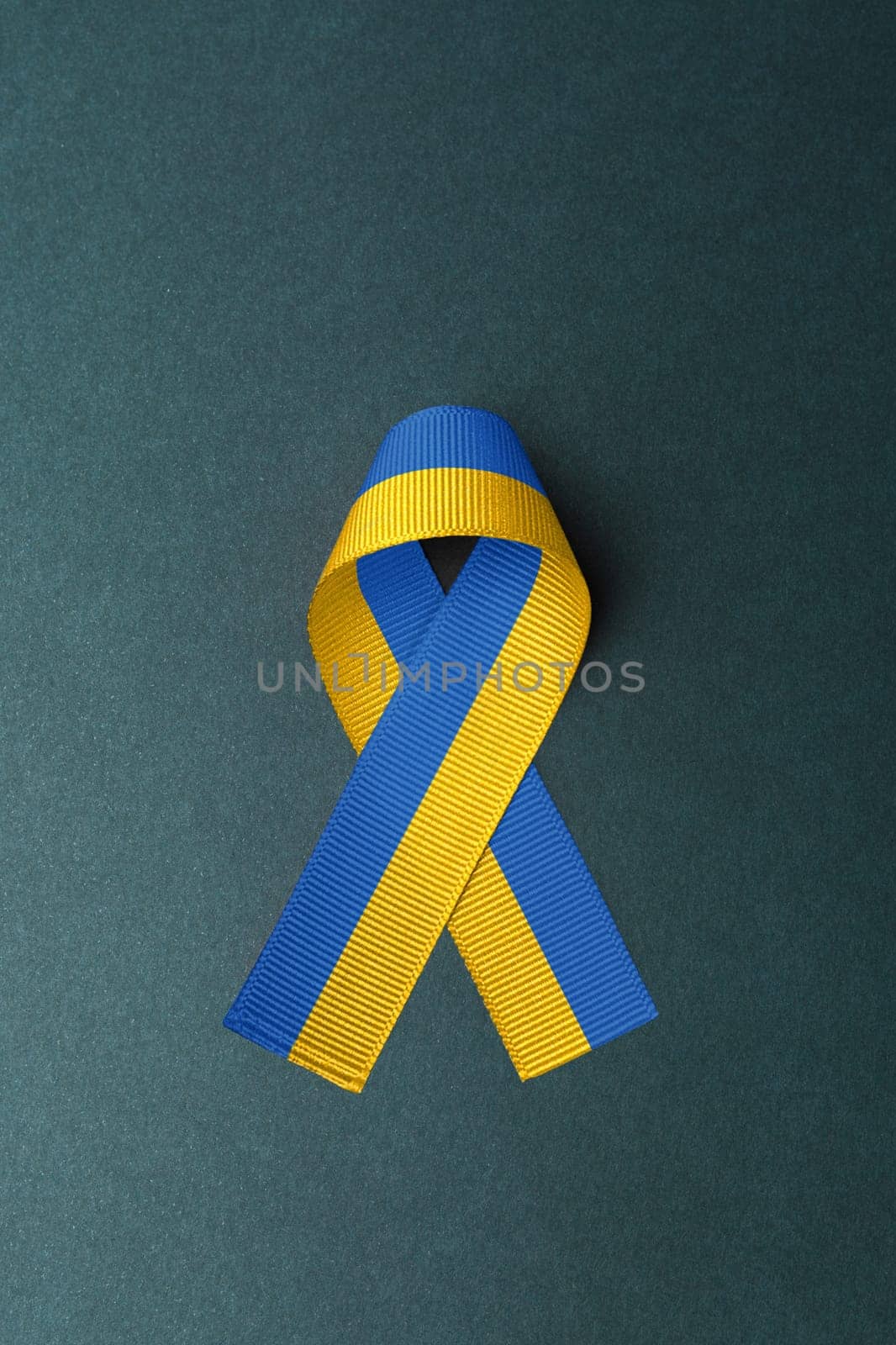 ukraine yellow blue ribbon in the middle of green table. concept needs help and support, truth will win