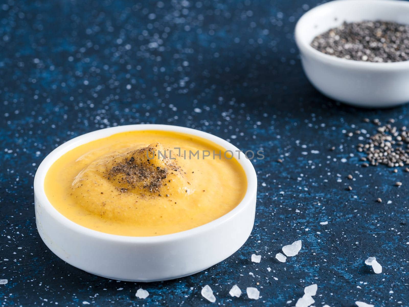 Creamy Cheddar sauce with chia seeds on dark background.Ideas and recipe for healthy diet or vegan food.Homemade Chia Cheeze Sauce for snacks,tacos,nachos,dipping,mac-n-cheese,base for pizza.Copyspace