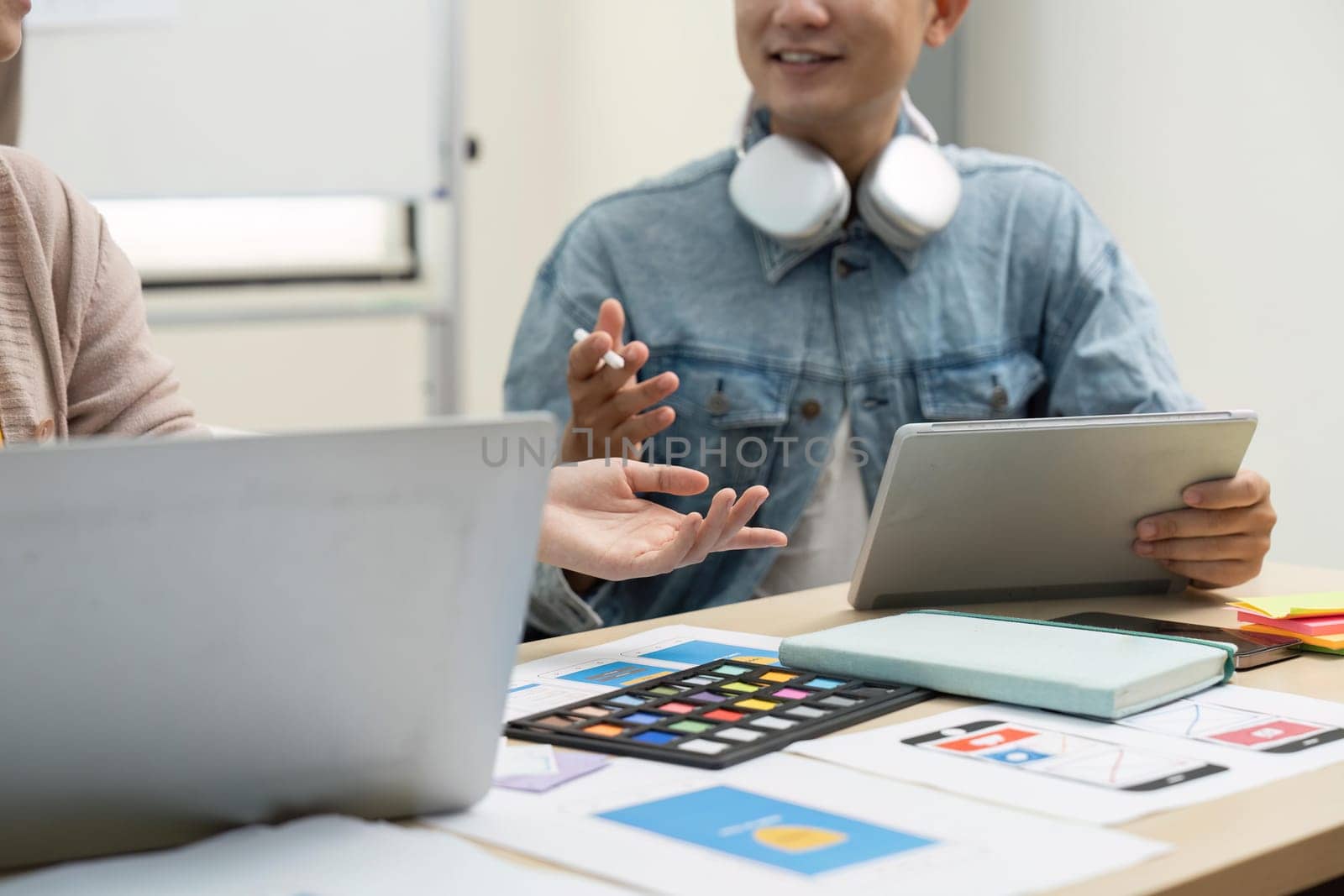 UX developer and UI designer brainstorming about app interface wireframe design on table with customer brief at modern office. Creative digital development agency.