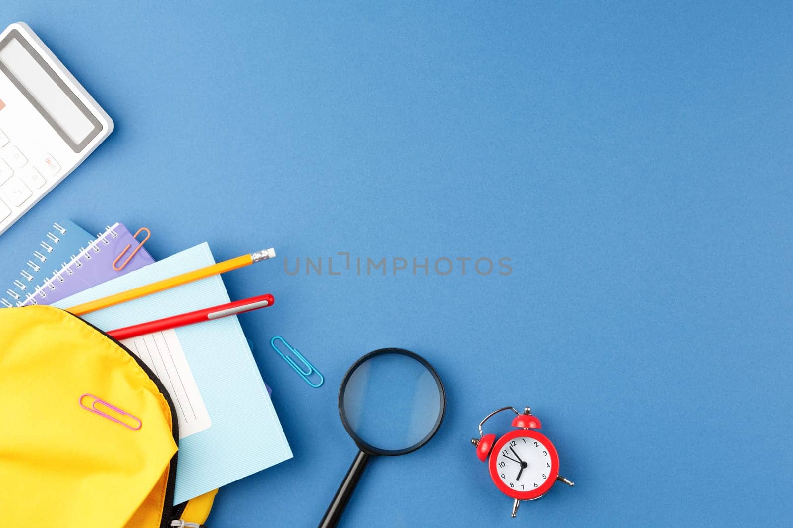 Back to school concept. Backpack with school supplies on blue isolated background. Flat lay.