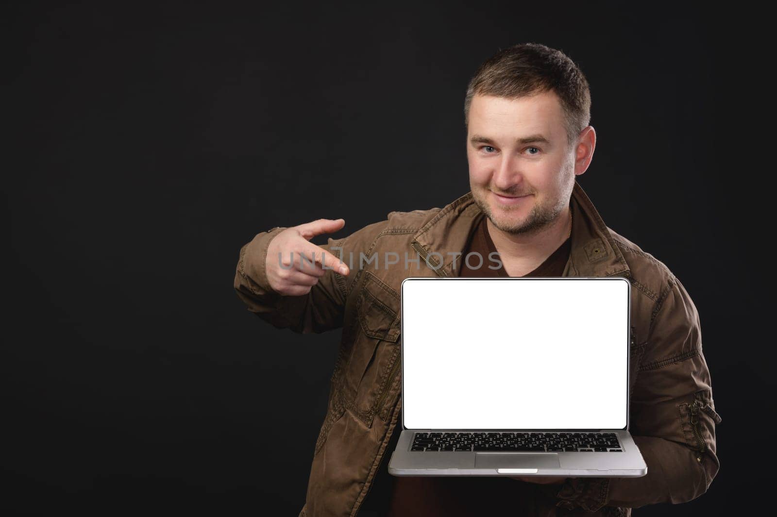 Happy mature attractive european man showing finger on laptop with blank screen isolated on white background. Advertising, great offer, website and recommendation from a professional. Remote work, freelance.
