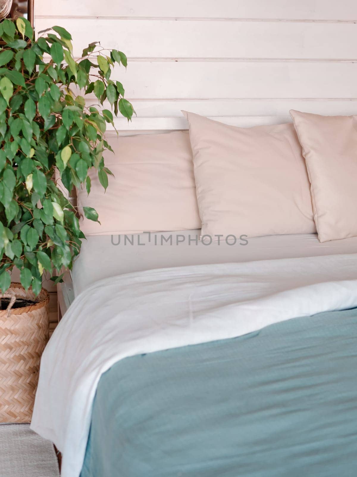 Bed in country house bedroom interior background. Green waringin tree near bed in scandinavian country house. Vertical. Copy space