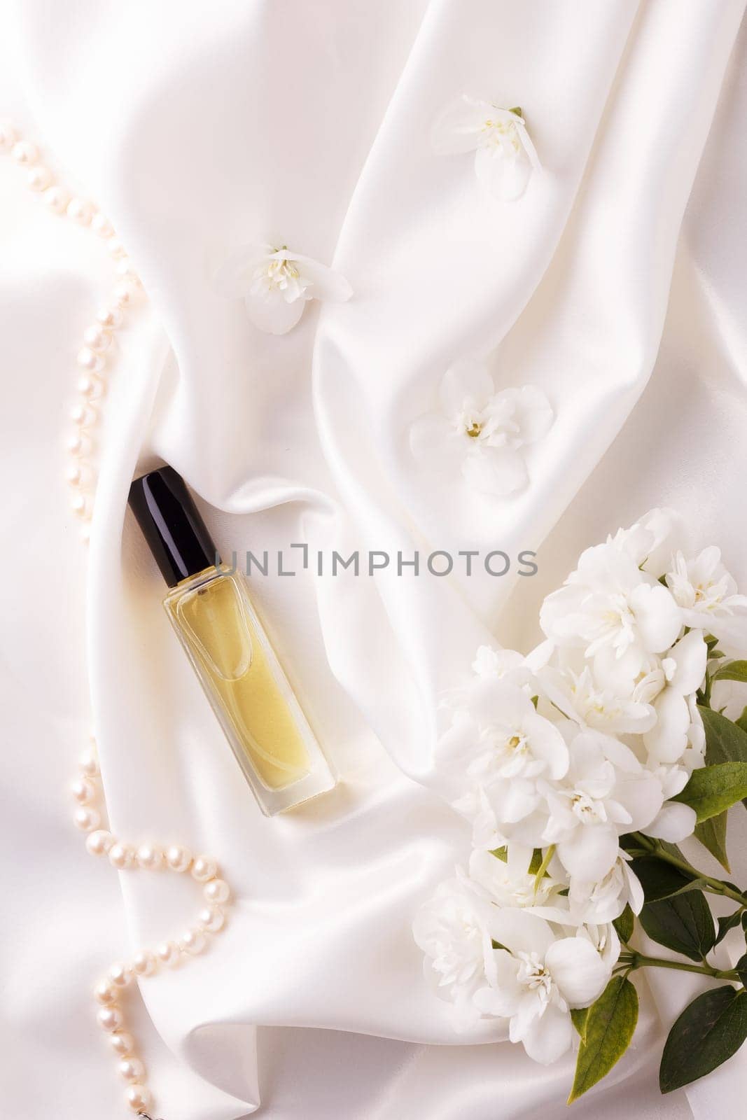 Perfume bottle with flowers on white satin fabric.