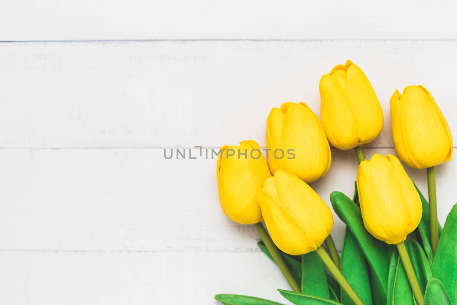 Top view of artificial yellow tulips on white table background for nature decoration and springtime concept