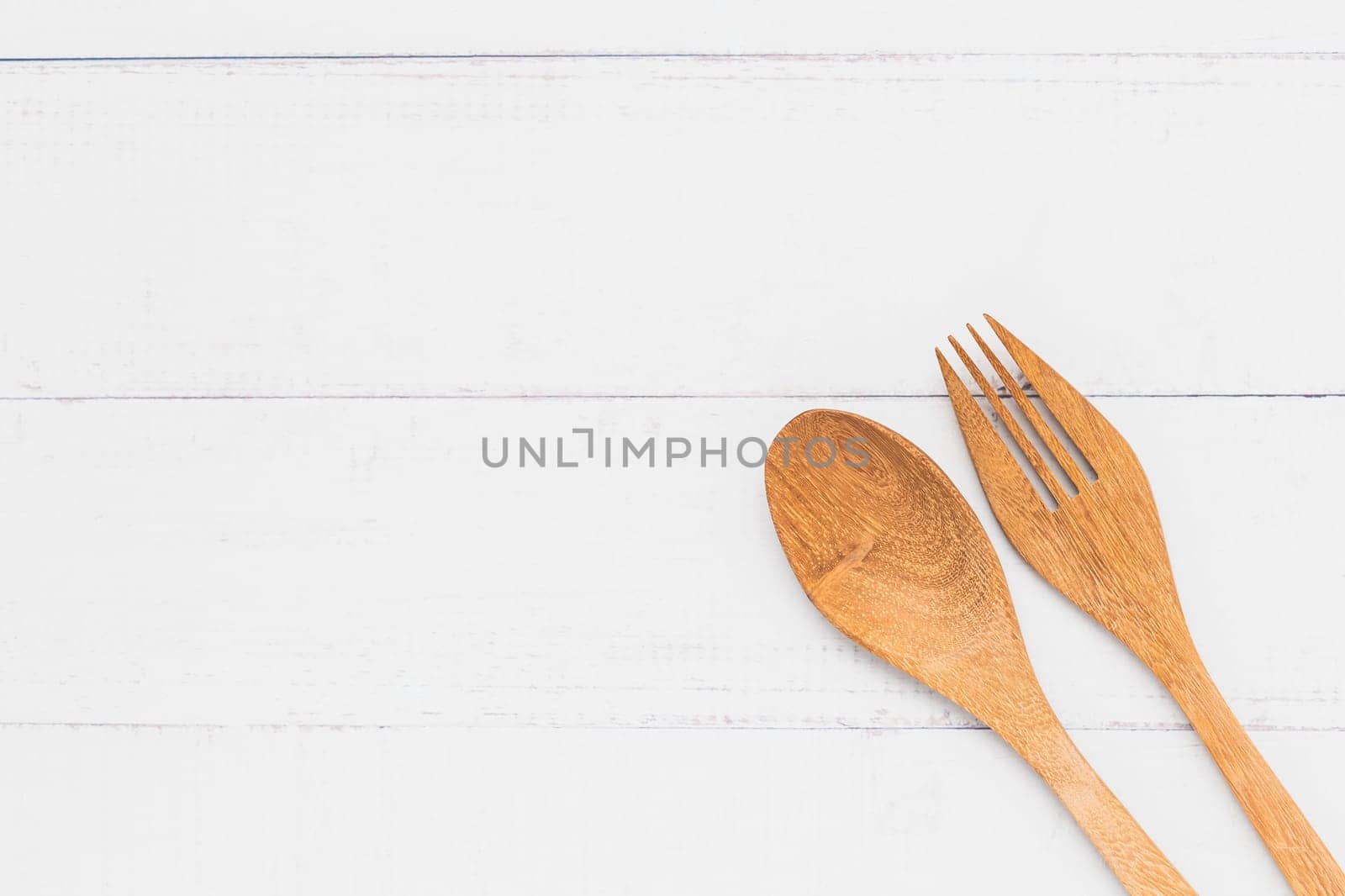 Top view of wooden spoon and fork on white table background for utensil and kitchenware concept