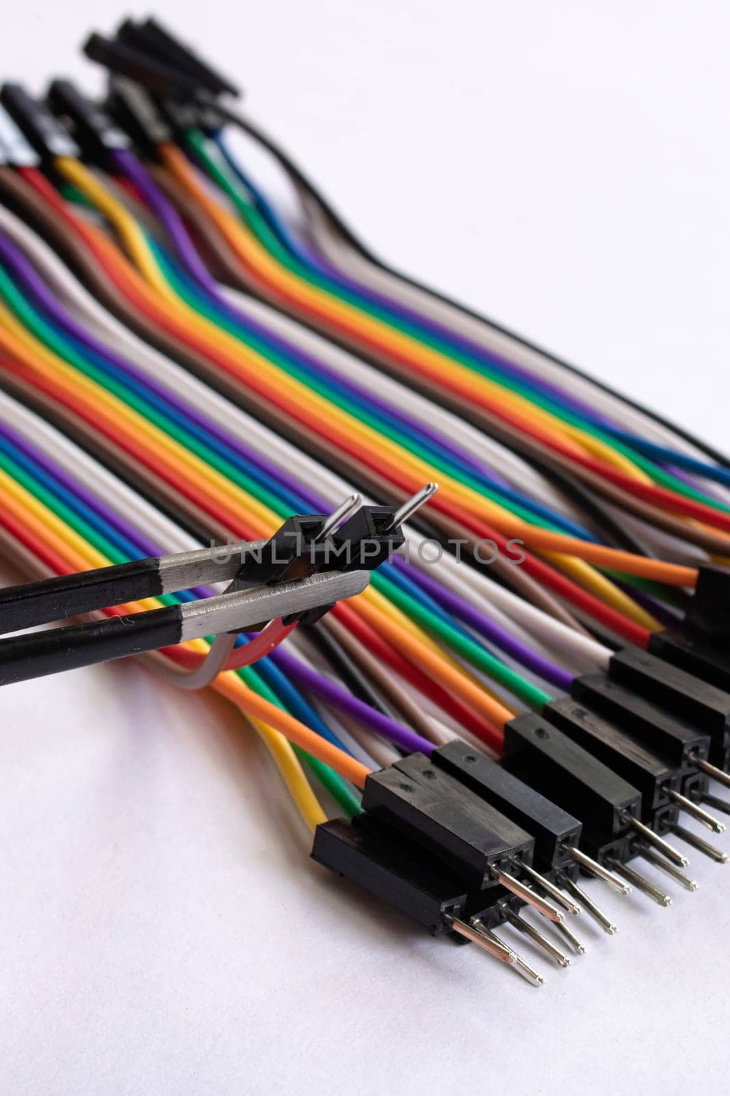 Multicolored computer wires and tweezers on a white background close up
