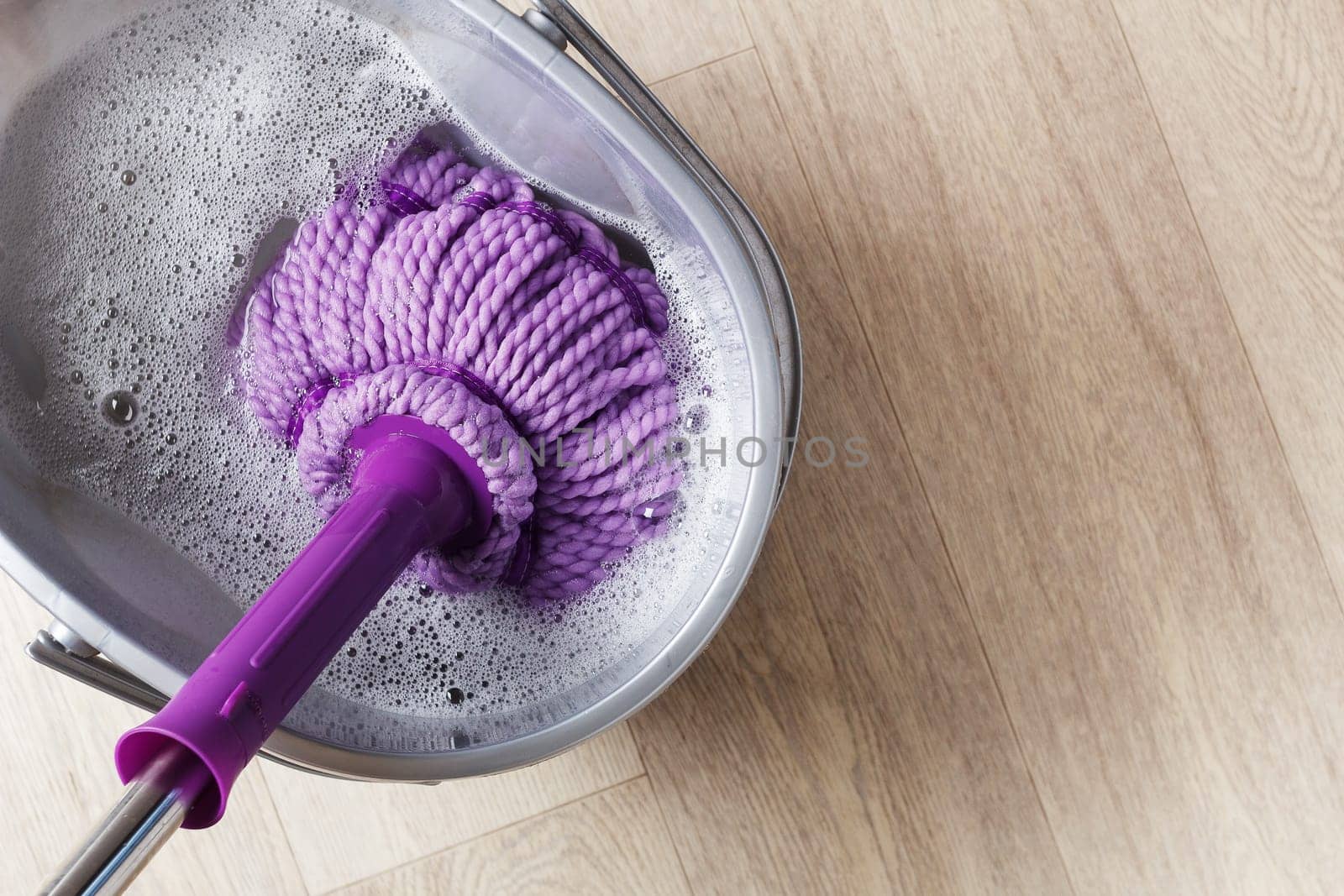 Purple mop in a bucket of water. The concept of indoor cleaning.copy space.