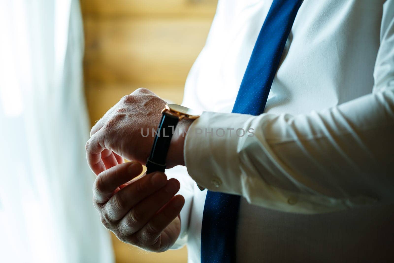 Man puts on a wedding suit and accessories on the wedding day. by Dmitrytph