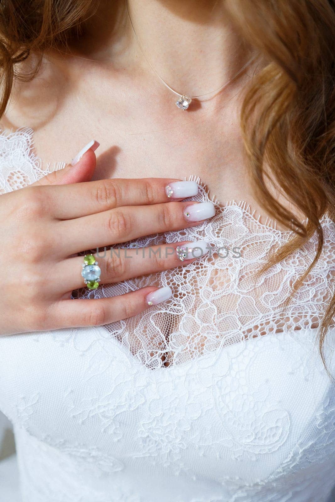 Bride's hands folded on a white wedding dress