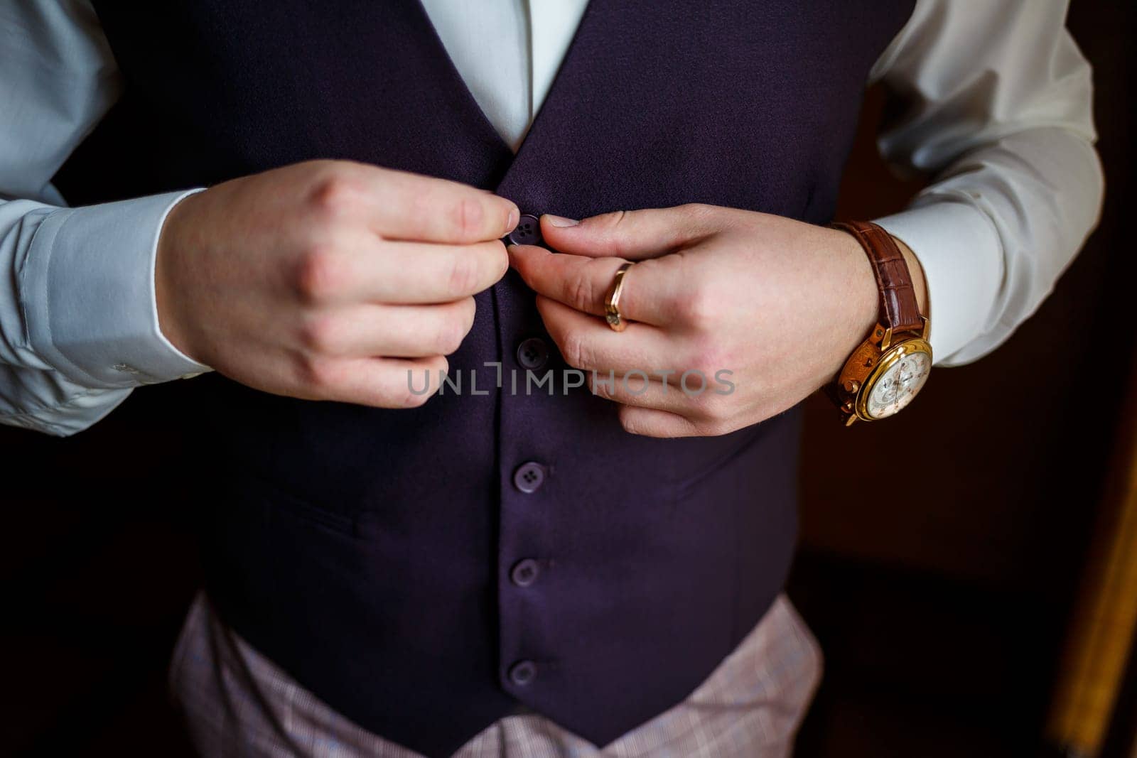 Man puts on a wedding suit and accessories on the wedding day.